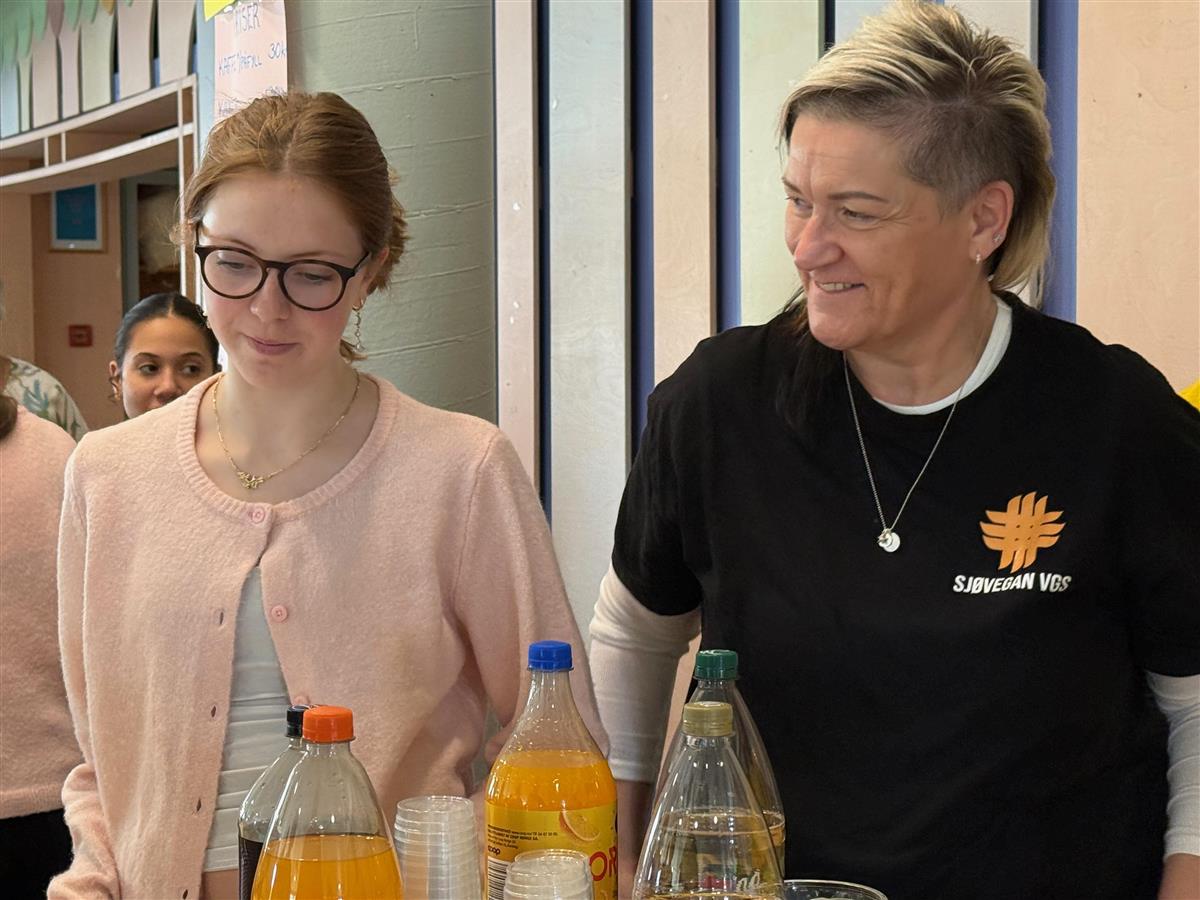 En lyskledd kvinne med briller står sammen med en mørkkledd kvinne - Klikk for stort bilde